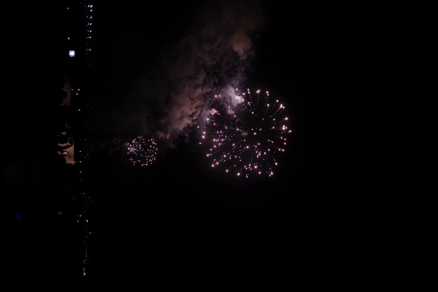 Fireworks bursting in a dark night sky over the ocean