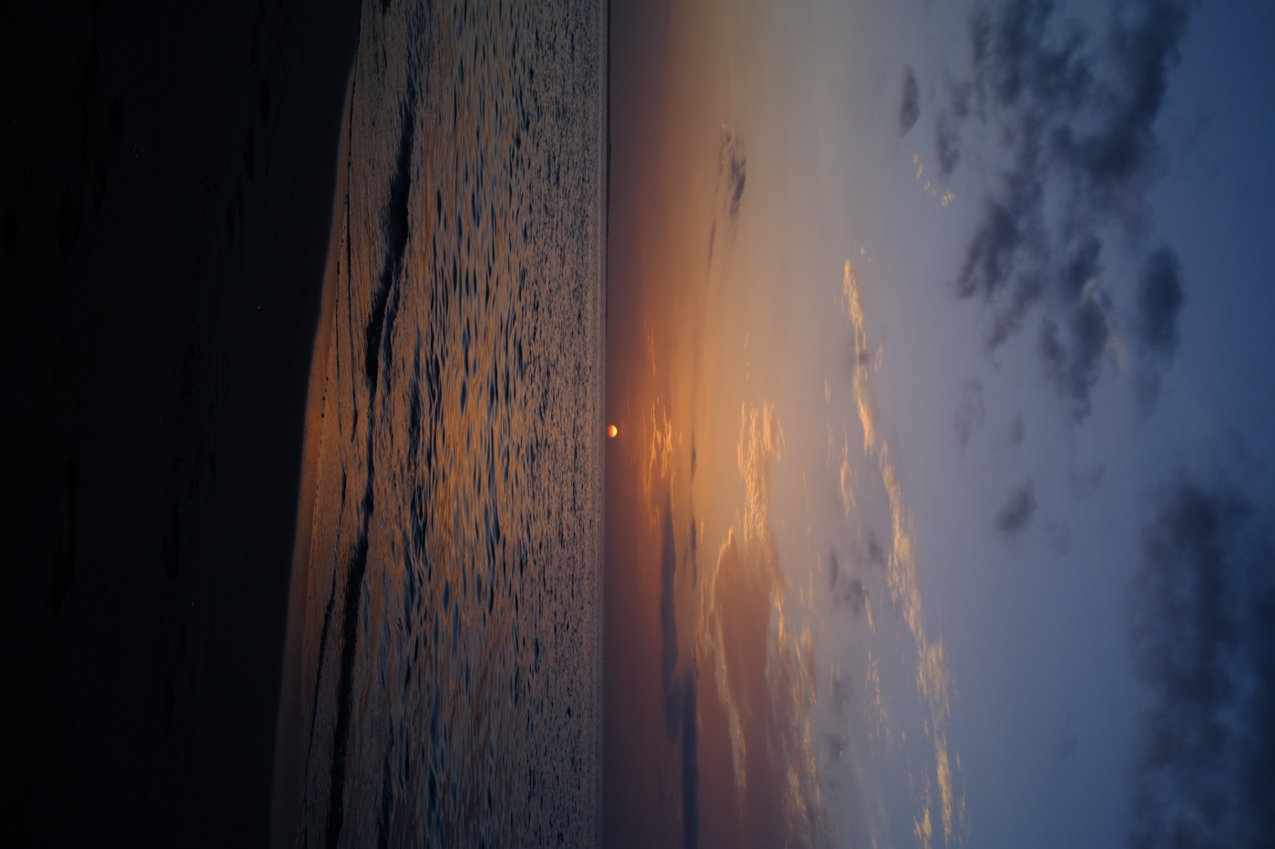 Sunset over calm water with a sandy beach in foreground